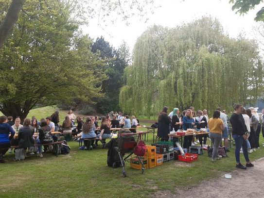 Mitten im Grünen (auf der Wiese vor der EF50) stehen viele Menschen um einen Grill. Das kann nur bedeuten, dass die Fachschaft ihr berühmtes Fachschafts- bzw. Fakultätsgrillen veranstaltet. Bei Bier und Softgetränken, sowie allerlei leckerer Nahrungsmittel sind die Studierenden sitzend oder stehend in Gespräche vertieft.